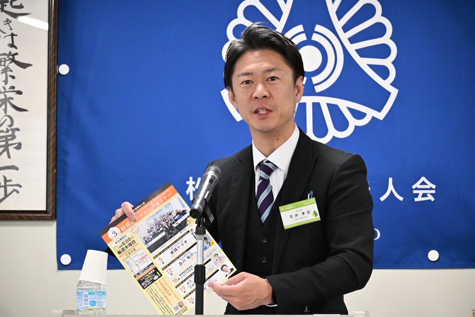 案内を手に連絡事項を伝える会員