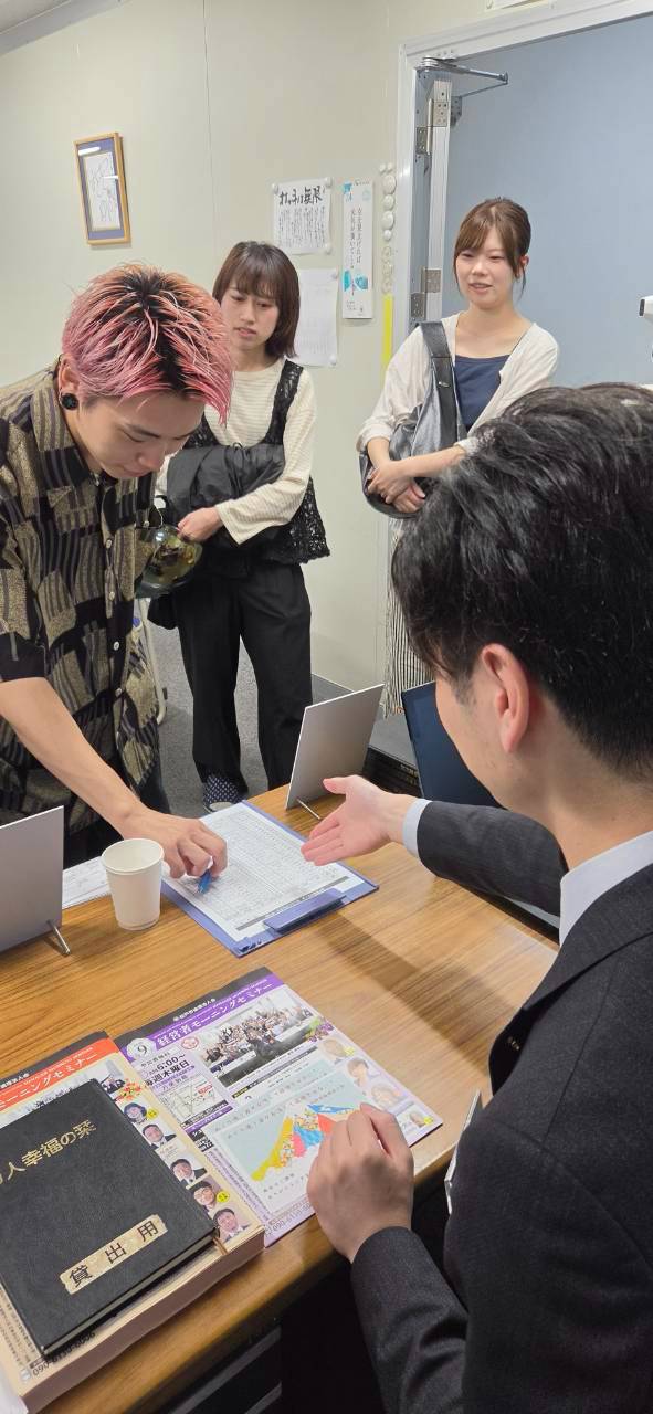 受付で記帳する参加者と、案内する会員